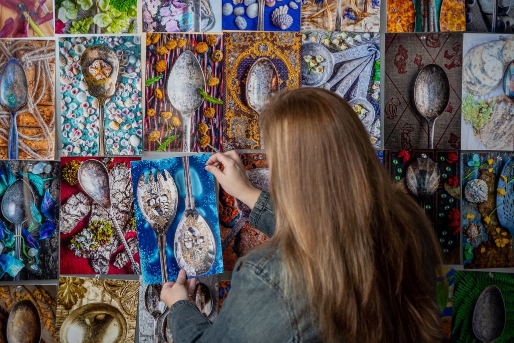 Artist Donna Dufault looking at a wall of prints from the Worn Spoon project